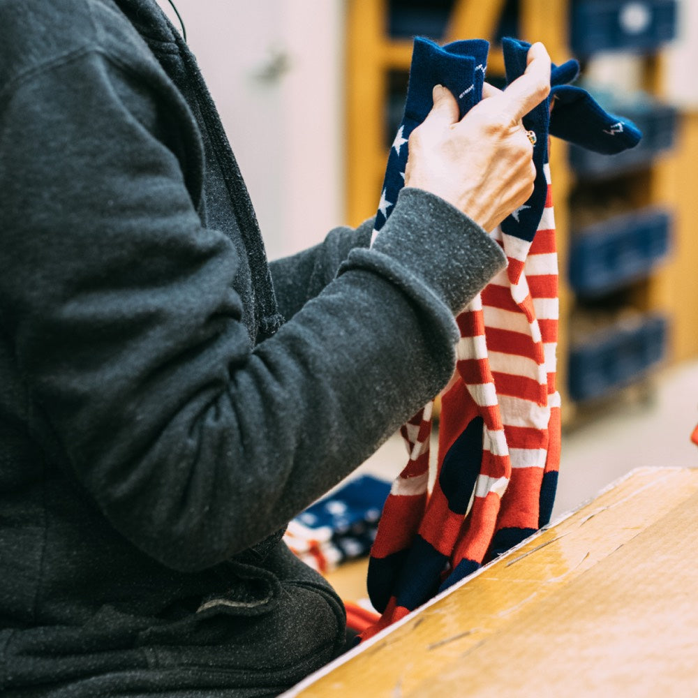Woman at darn tough folding the Americana socks made in USA