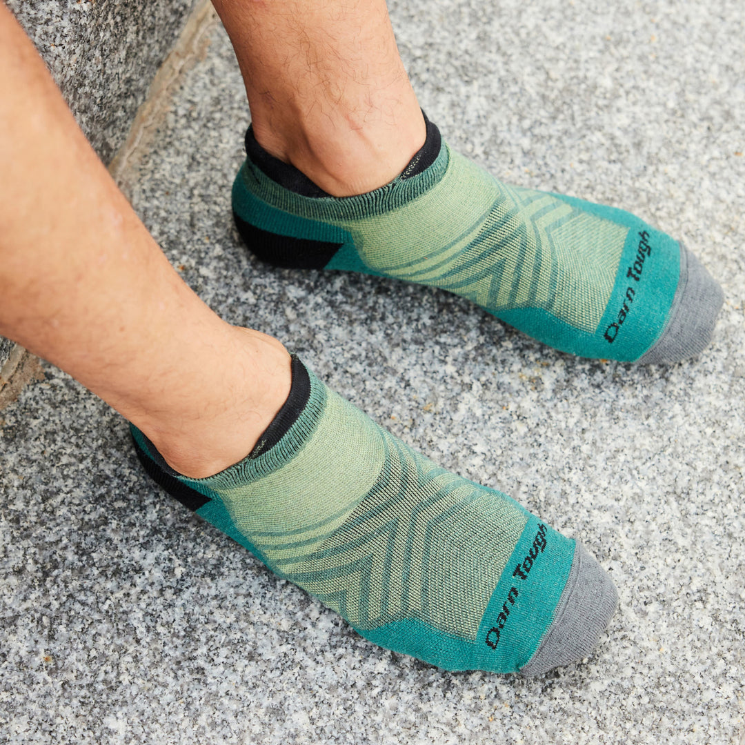 Models feet on granite step wearing the No show Run cushioned sock in teal.