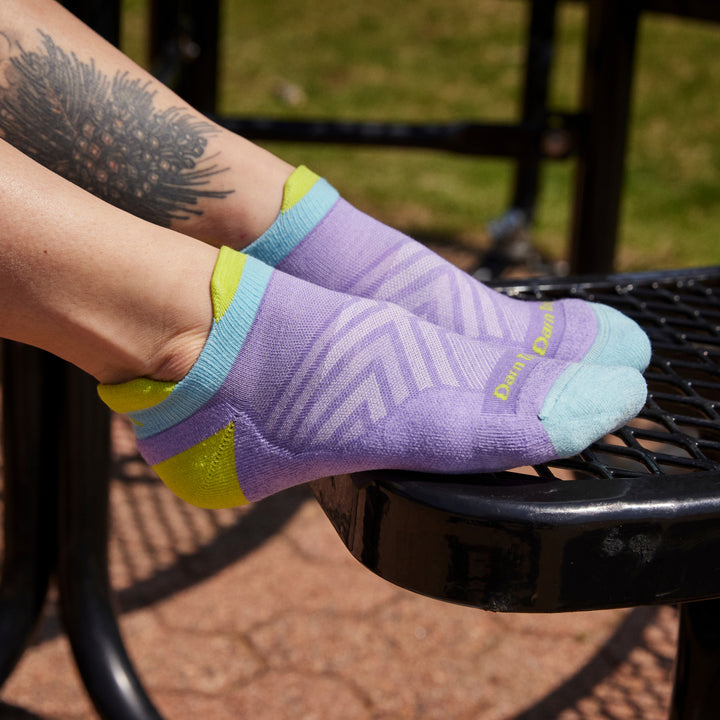 Close up shot of model sitting on black picnic table wearing 1047 socks in Lavender without shoes on