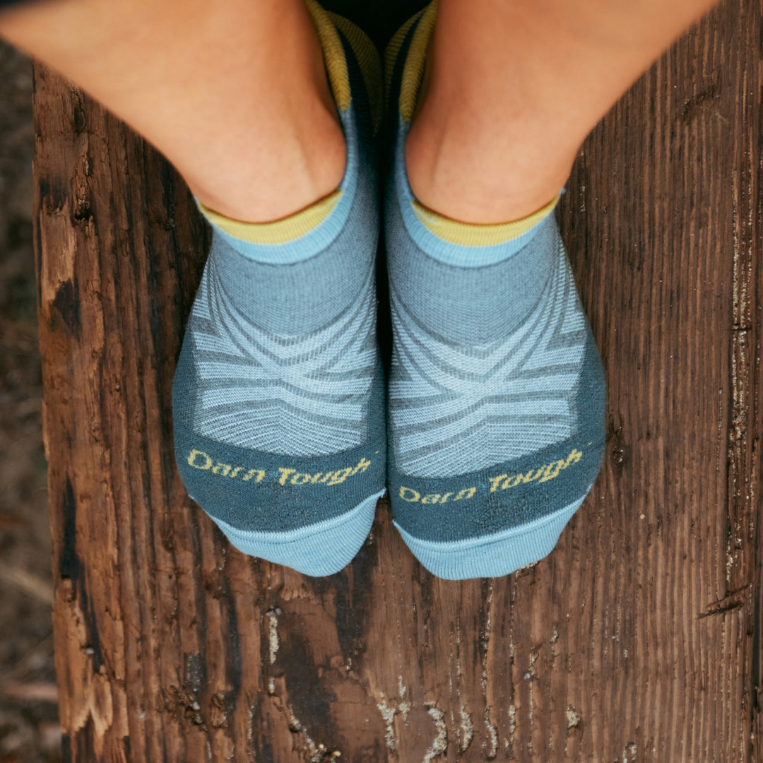 top down shot of models' feet on wood wearing the 1047 women's no show running sock in teal colorways