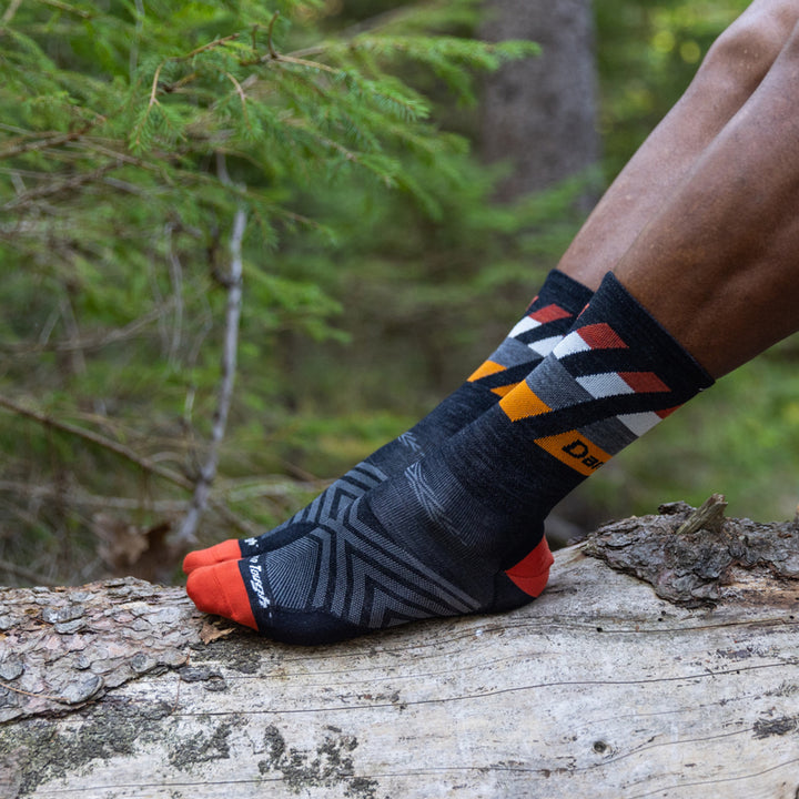 Close up shot of model with their feet on a rock wearing the men's grit miciro crew running socks in black