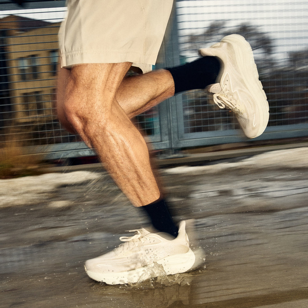 close up of man running through puddles in front of fence wearing 1071 run micro crew ultra light weight with cushion black sock