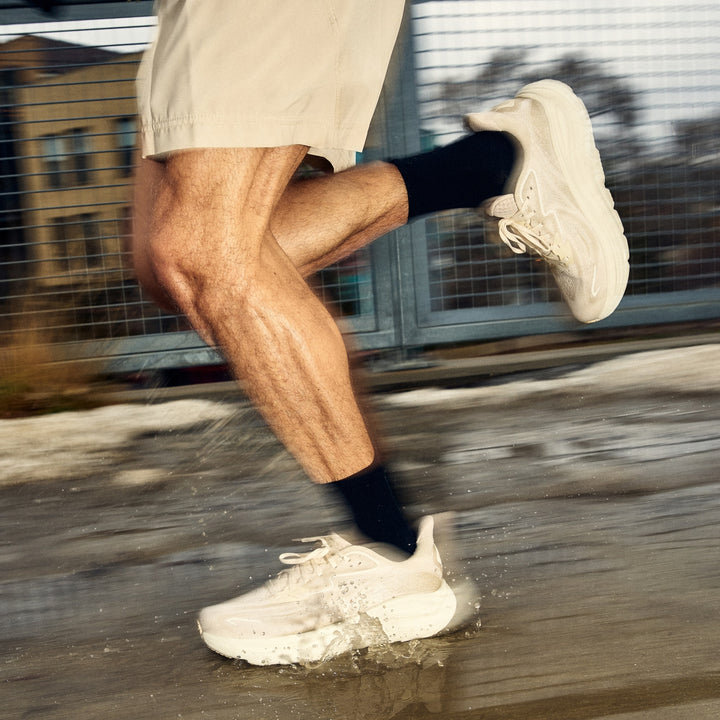 close up of man running through puddles in front of fence wearing 1071 run micro crew ultra light weight with cushion black sock