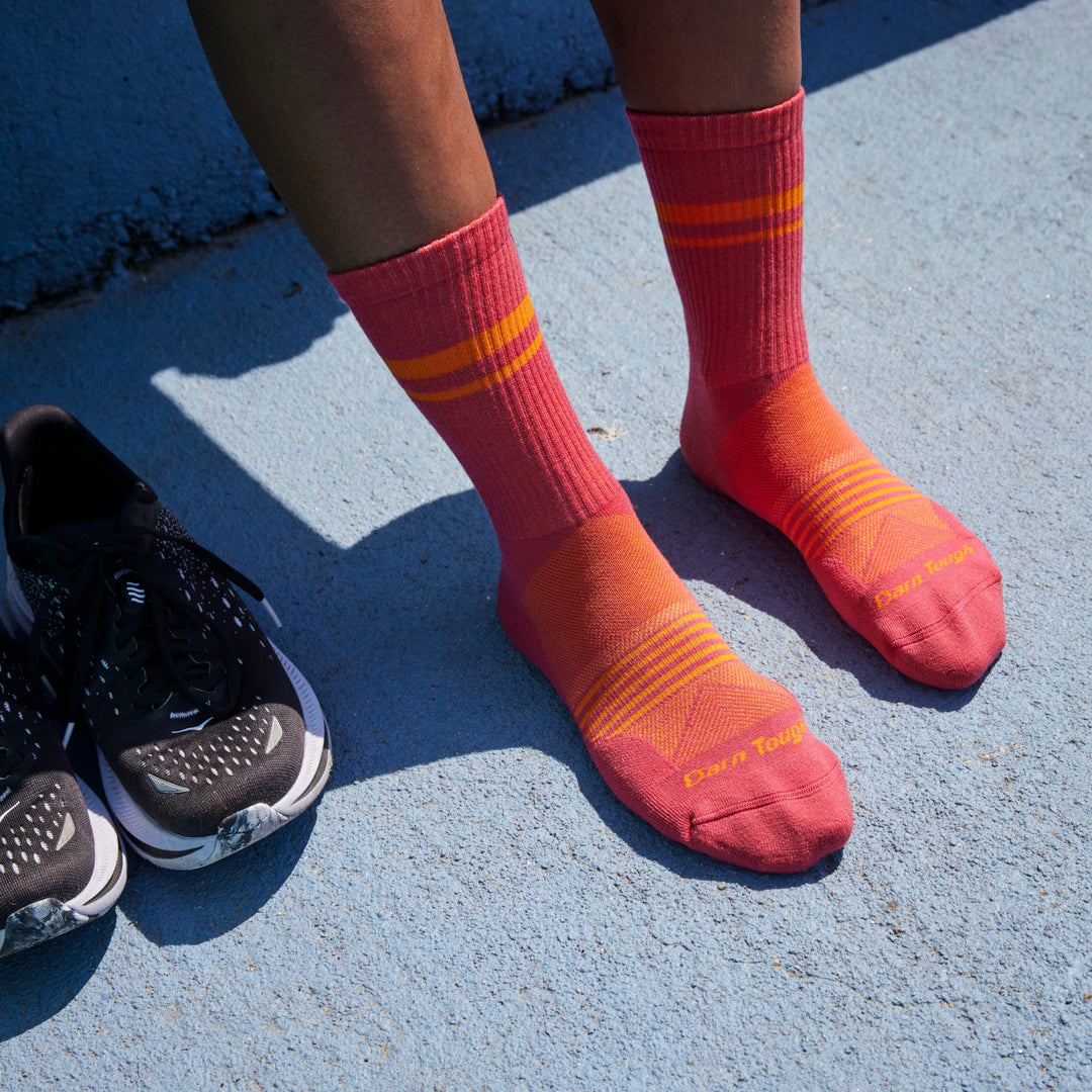 Close up shot of model wearing 1114 socks in Raspberry colorway against blue painted concrete background
