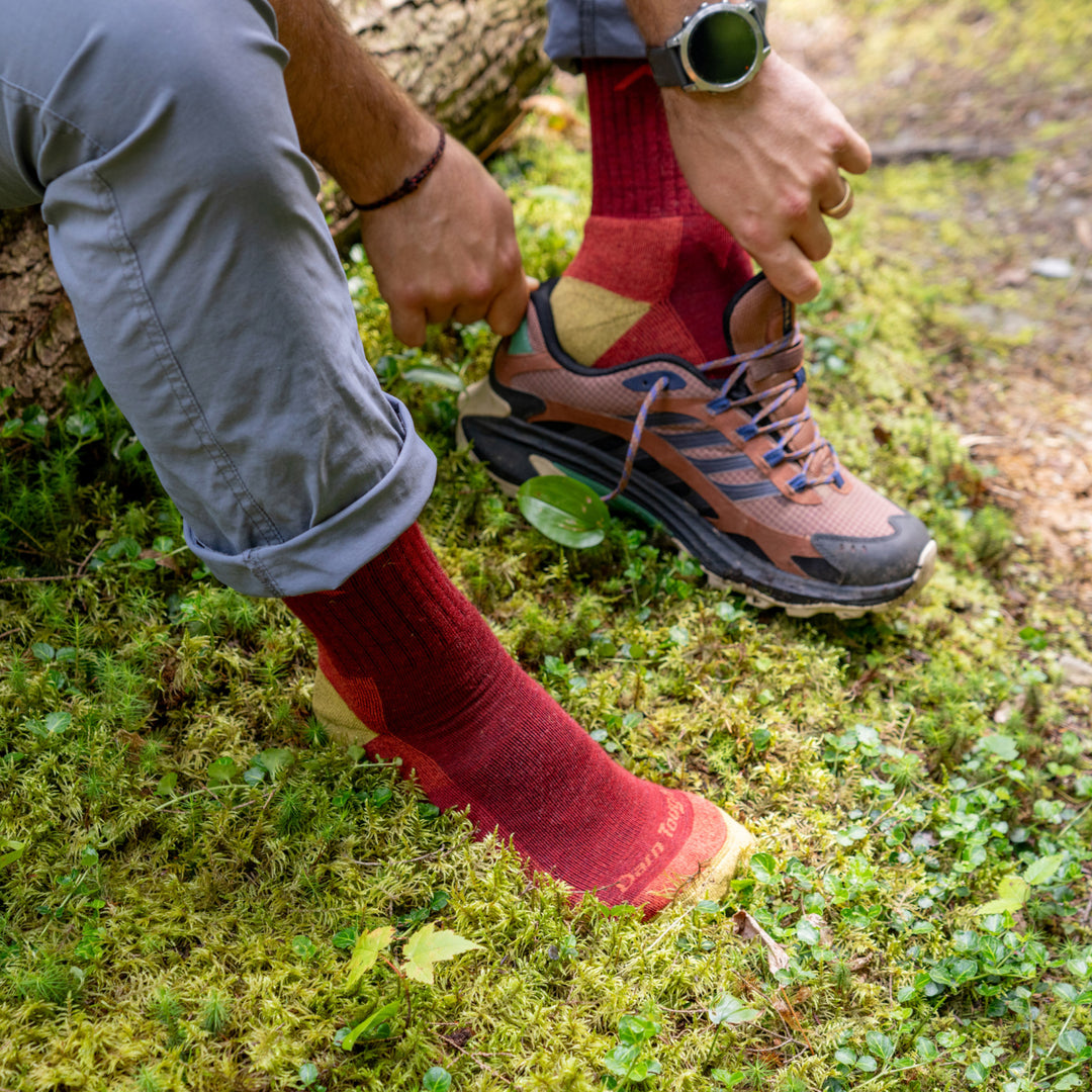 model sitting on down tree putting on shoes wearing the 1466 micro crew hiker in berry 