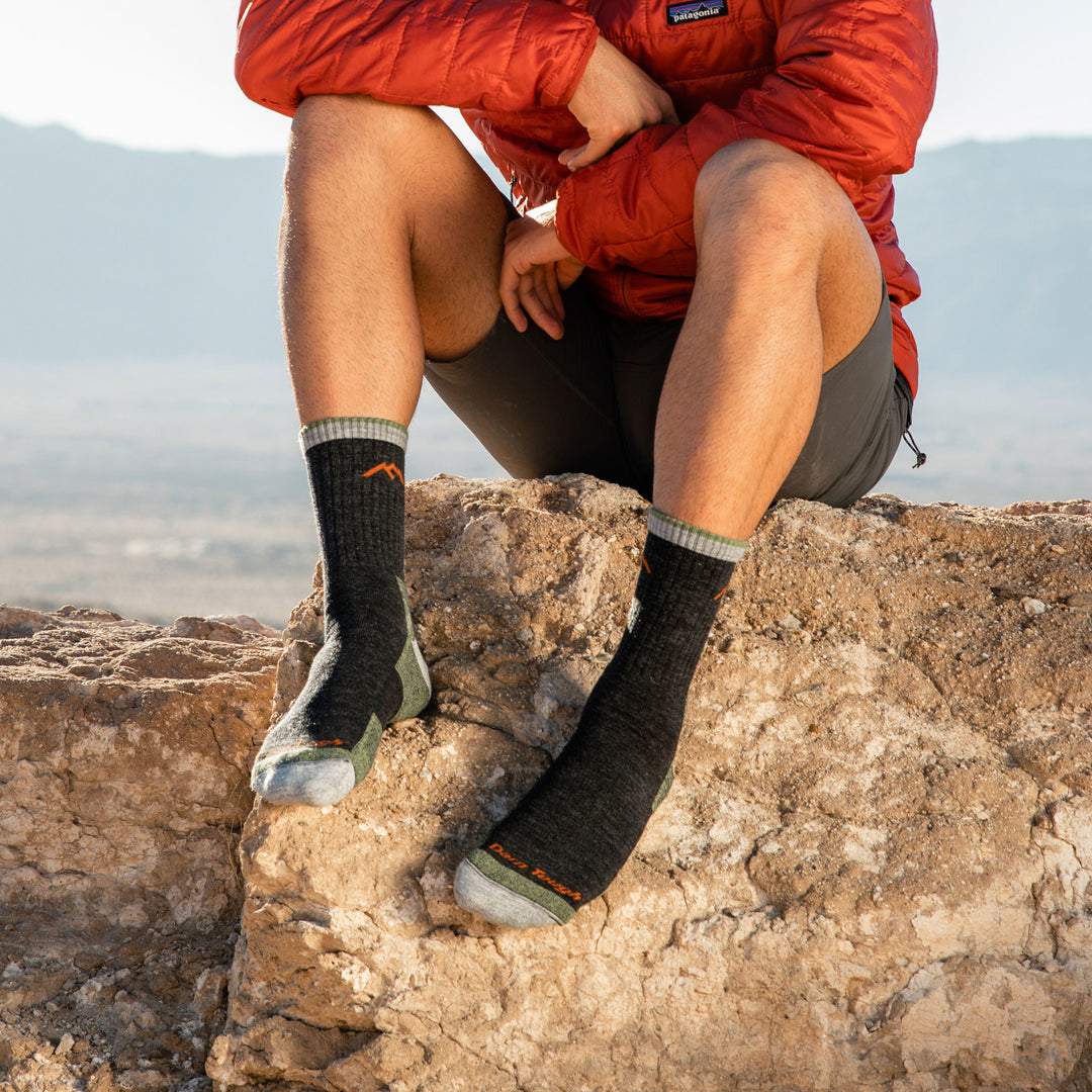 Close up shot of model sitting on rocks wearing men's hiker micro crew hiking sock in lime