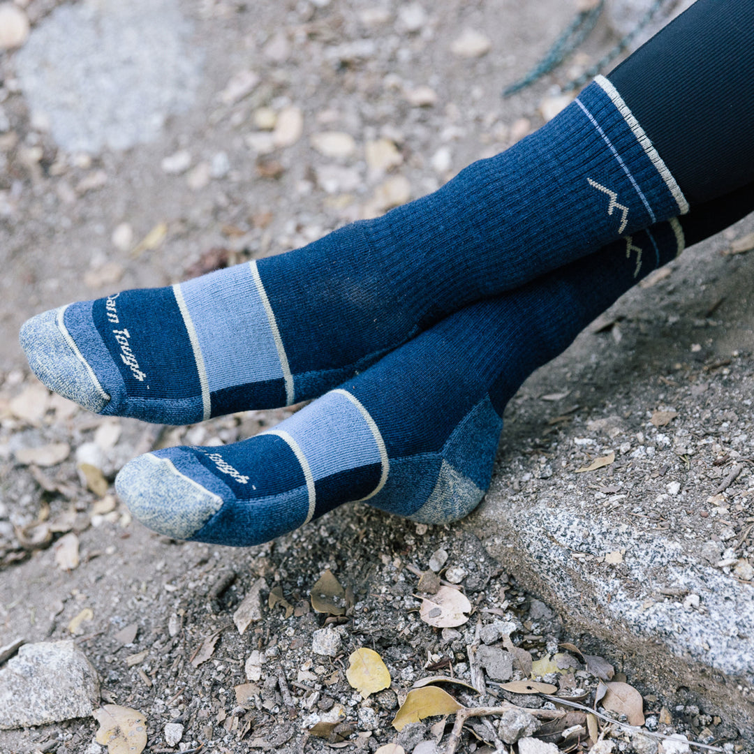 Close up shot of model wearing women's hiker boot hiking sock in navy eclipse with rocks in background