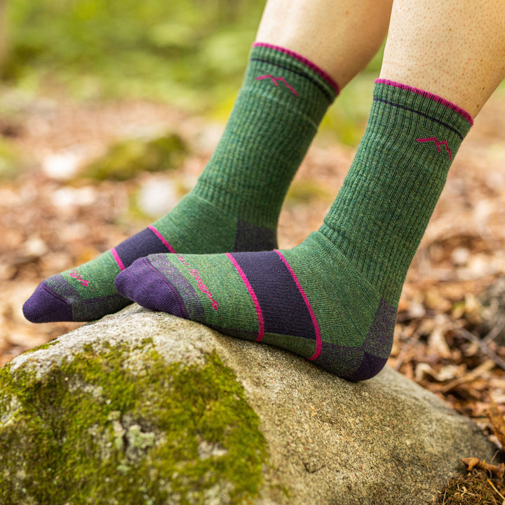 Close up of a woman resting her feet on a rock, barefoot, wearing Women's Hiker Boot Midweight Hiking Socks in Moss