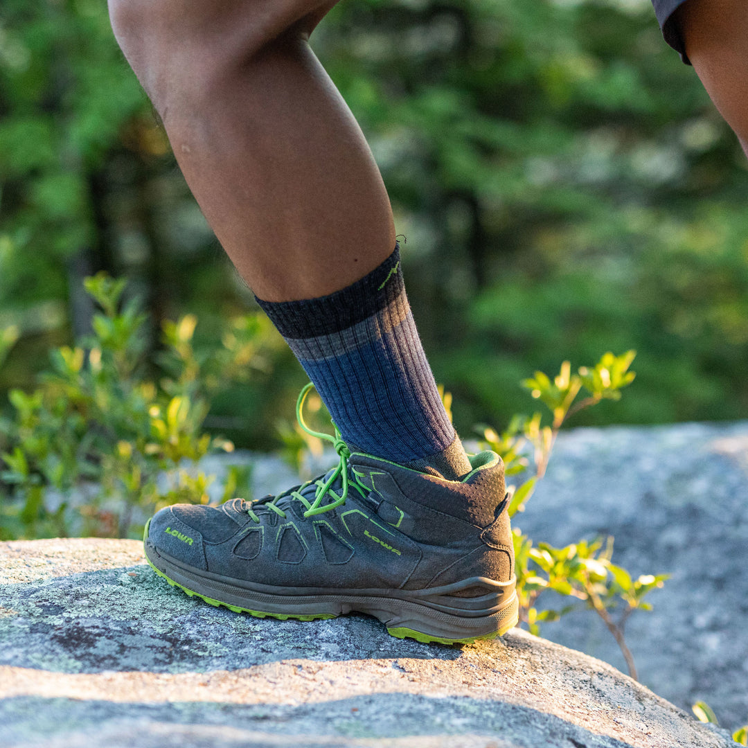 Man stepping on a rock in a hiking shoe and wearing Heady Stripe Micro Crew Hiking Sock in Blue