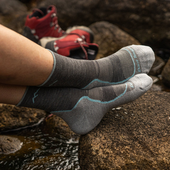 Woman rests her feet on a rock, ankles crossed with hiking boots in the background, wearing Women's Light Hiker Micro Crew Lightweight Hiking Socks in Slate, Lifestyle Image