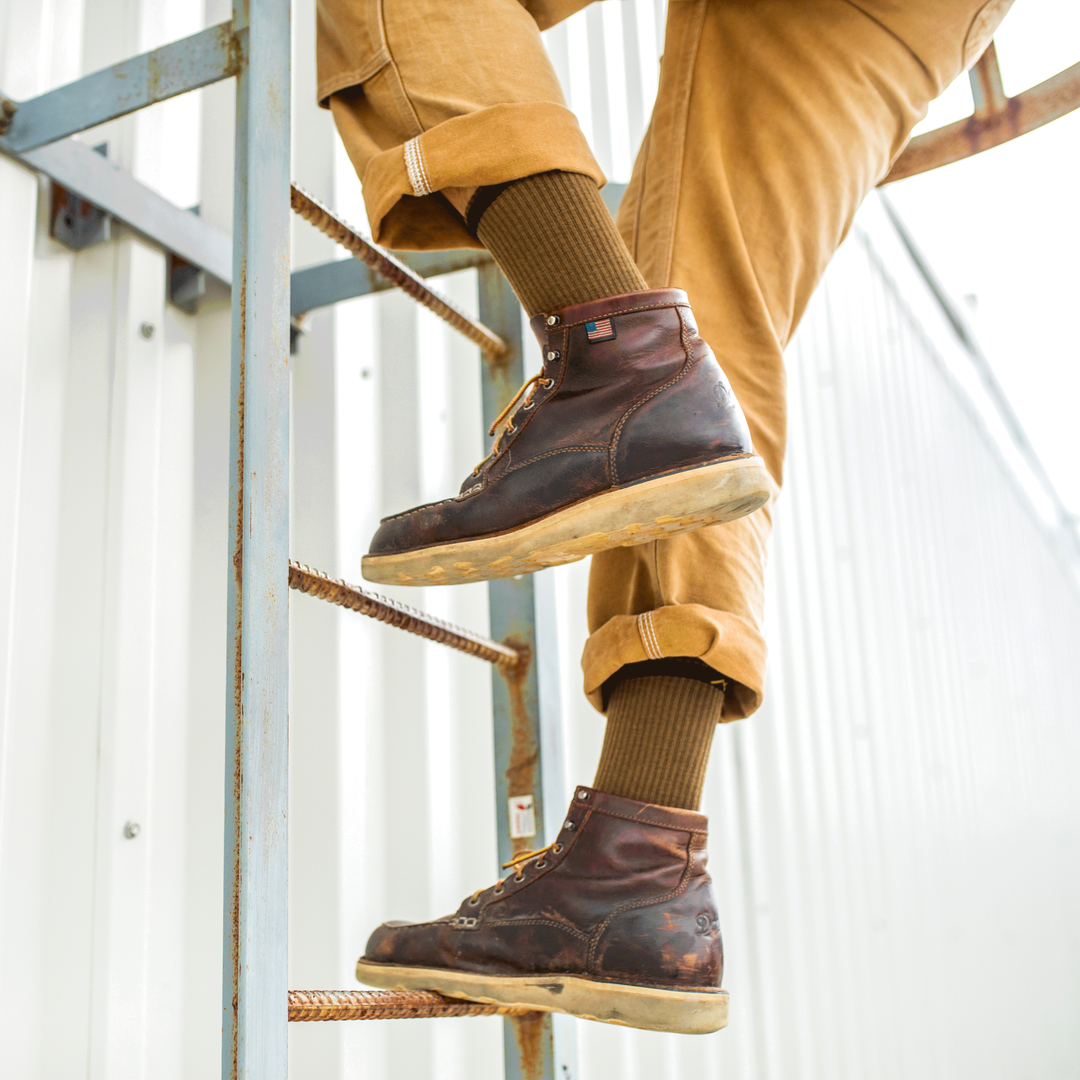 Worker going up ladder wearing leather work shoes and Fred Tuttle work socks in timber