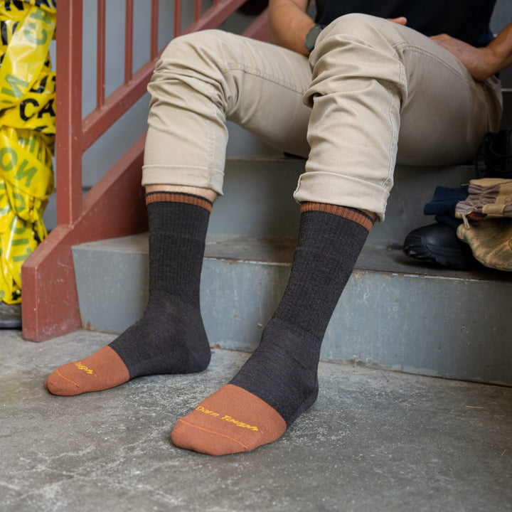 Model sitting on stairs with feet on the concreate wearing the 2006 steely boot in walnut