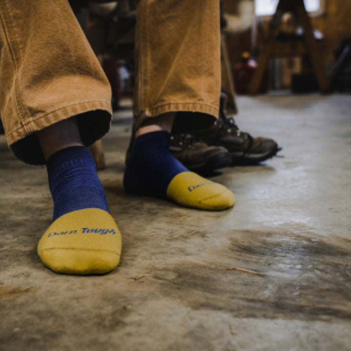 Close up shot of model sitting in shop wearing 2204 socks in Indigo colorway without shoes on