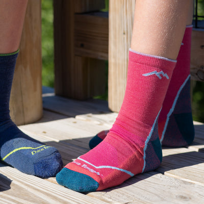 Close up shot of model sitting on a deck outside wearing the juniors light hiker micro crew hiking sock in raspberry