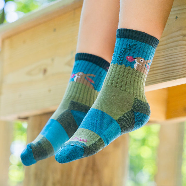 Close up shot of model sitting on a railing wearing the juniors bubble bunny jr micro crew hiking sock in willow