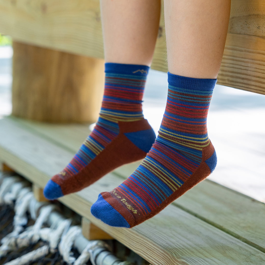 Close up shot of model sitting on a bench wearing the juniors zebra canyon micro crew hiking socks in marine blue