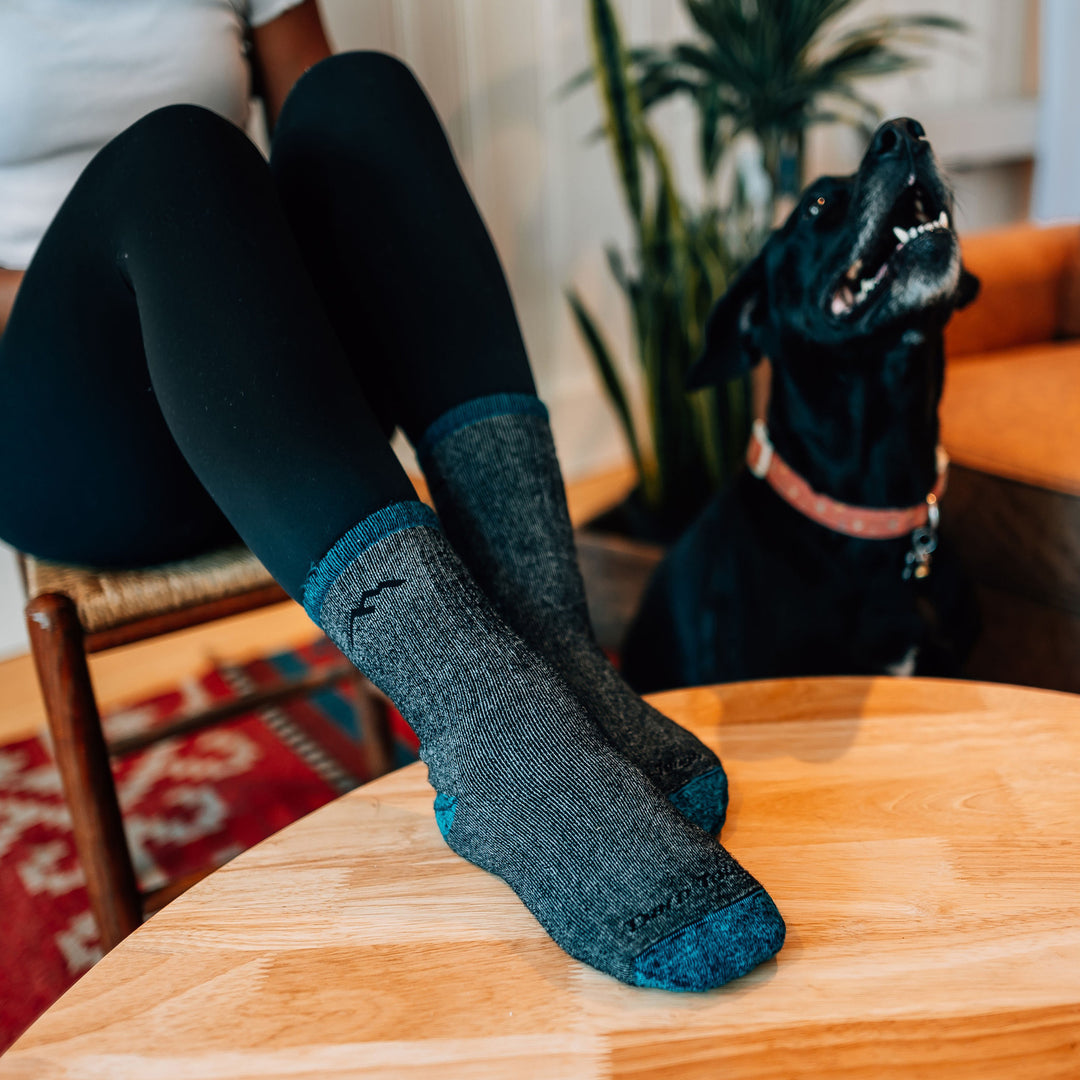 Model with her feet on a coffee table wearing the women's mountaineering micro crew hiking socks in midnight