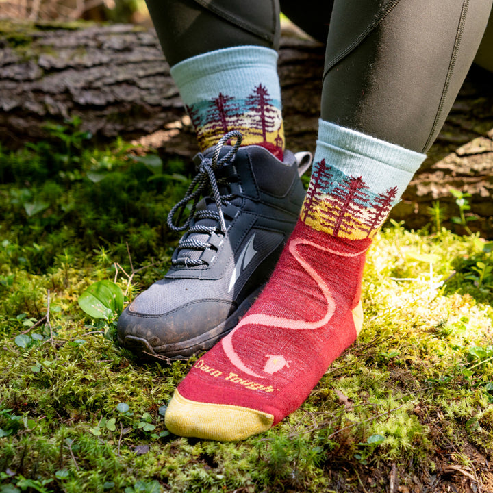 Model sitting on down tree with feet in the moss wearing the 5013 northwoods in Berry 