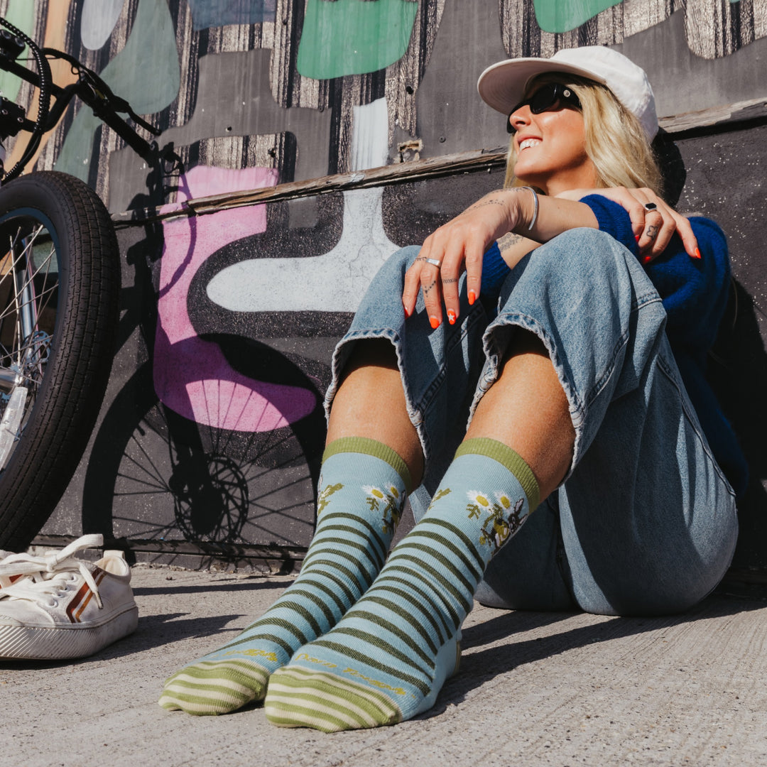 Model sitting on the ground with feet out in front wearing the 6037 animal haus lightweight lifestyle crew sock in bunny blue colorway