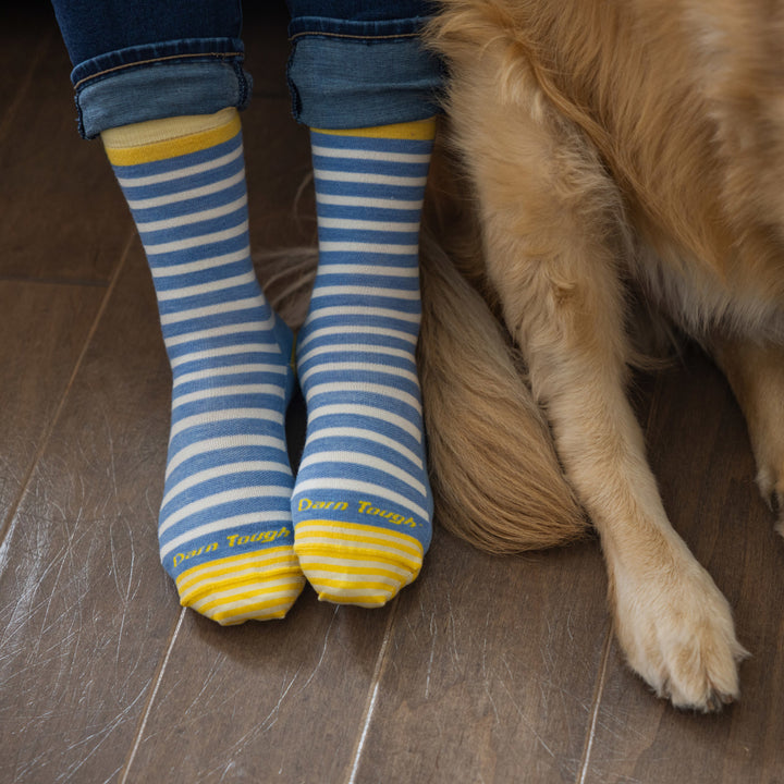 Models feet next to a do on wood floor wearing the 6039 Morgan Crew Lifestyle sock in Country Blue