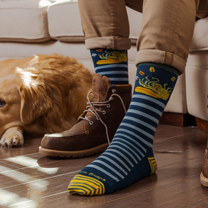 Models feet on wood floor with one shoe of wearing the 6066 Animal haus Lifestyle Crew socks in Dark Teal 