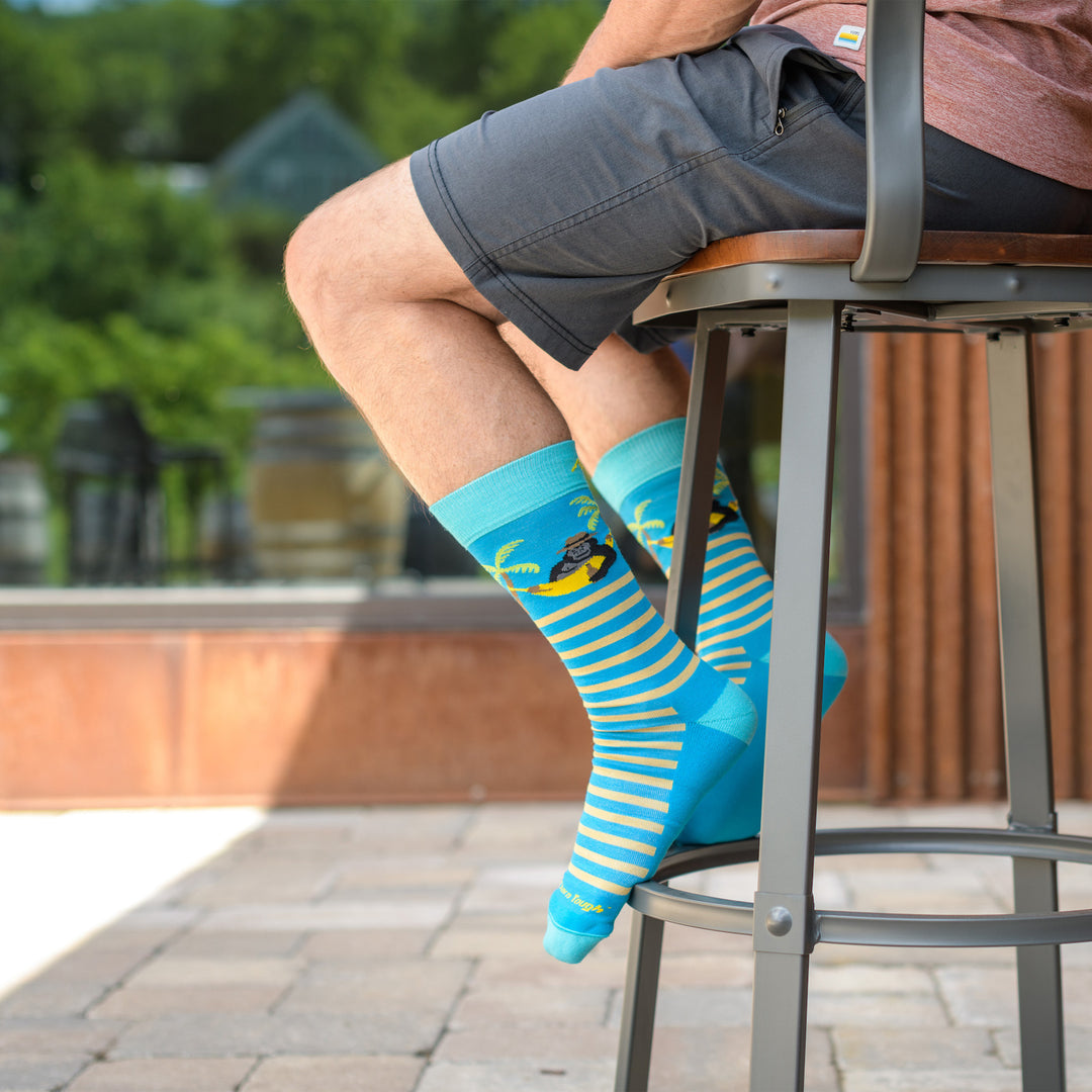Close up shot of model sitting in a high top chair wearing the men's wild life crew lifestyle socks in ocean blue