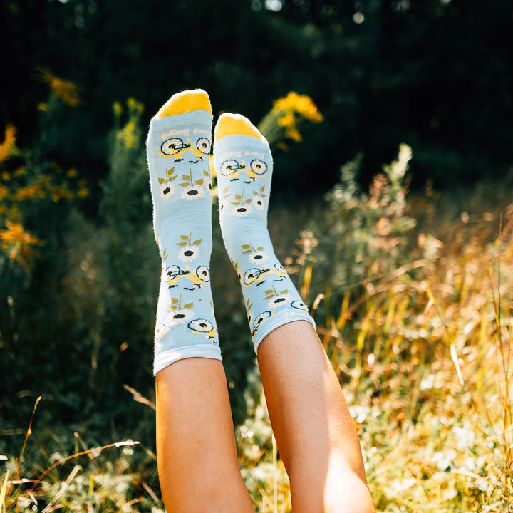 Close up shot of model laying in a field wearing the women's sun pedal crew lifestyle socks in glacier blue