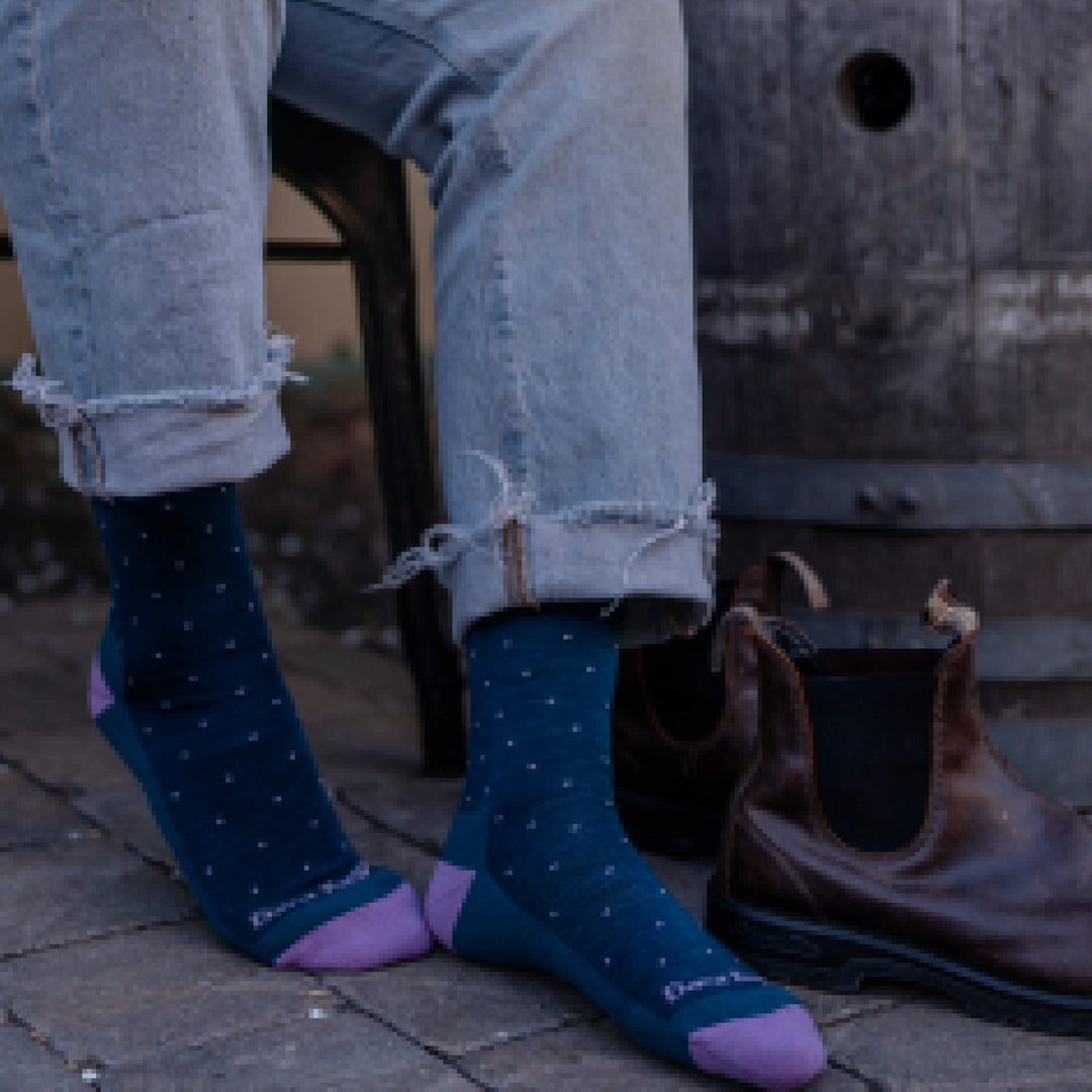 Close up shot of model sitting on a stool wearing 6110 socks in Dark Teal colorway without shoes