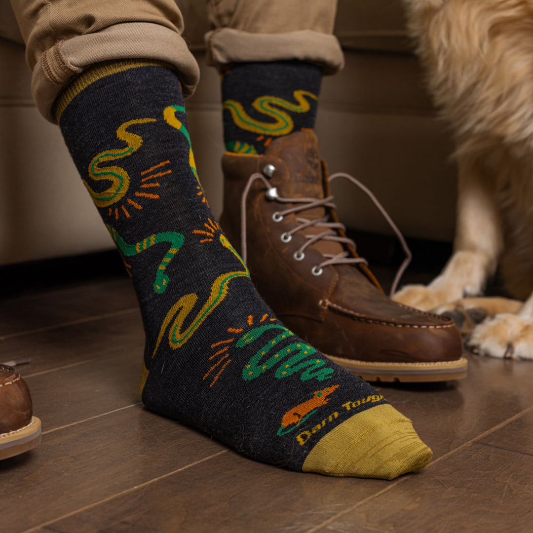 Models feet on wood floor with one shoe off wearing the 6119 Field guide Crew Lifestyle sock in Charcoal 