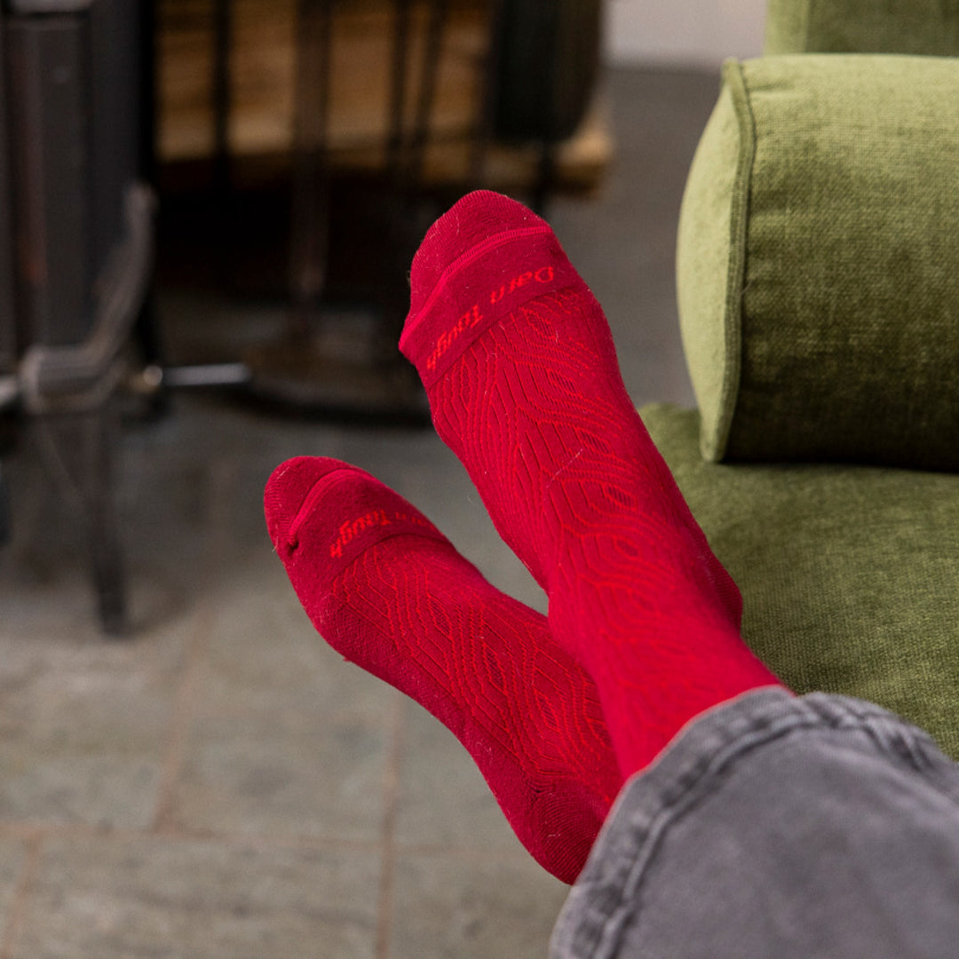 close up image of womans feet crossed on couch wearing 6140 cable crew lightweight with cushion burgundy sock