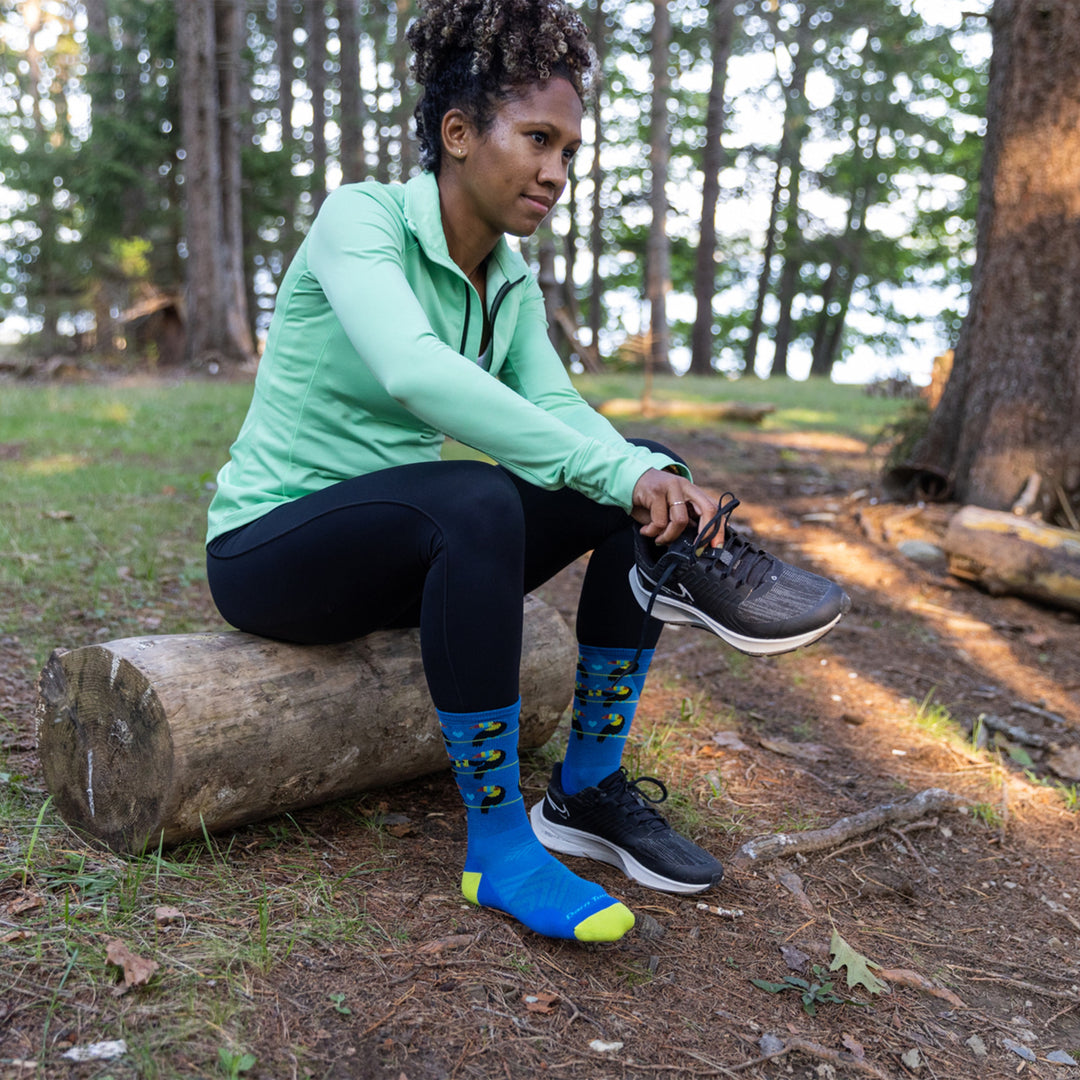 Model putting on her running shoes while wearing the women's toco loco micro crew running socks in baltic blue