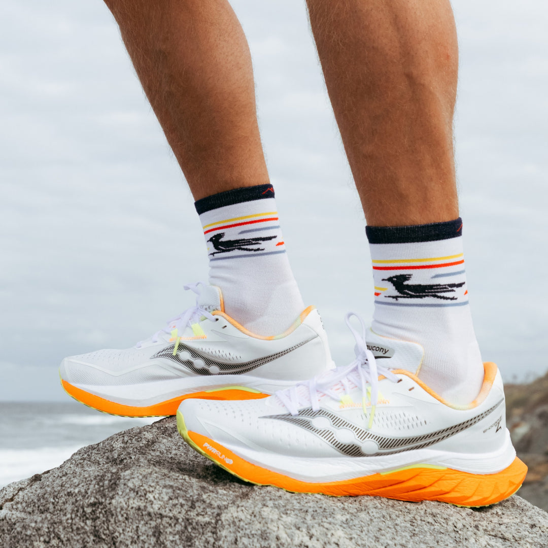 close up model feet in sneakers standing on rock wearing the 1062 front runner micro crew running sock in white colorway