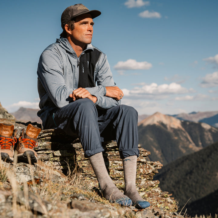 model sitting on a mountain top feet in the rocks wearing the 1403 boot hiker in rye colorway