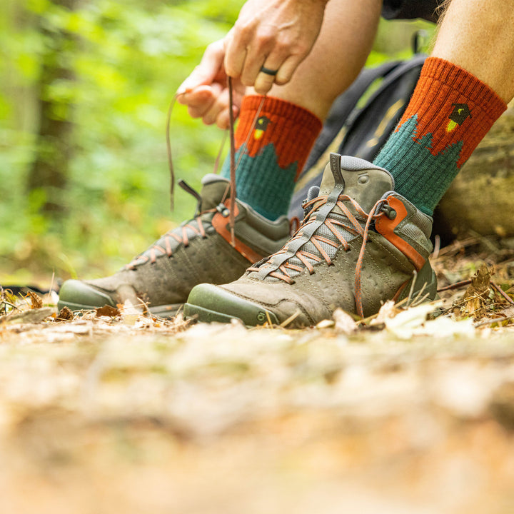 Close up shot of model sitting on a trail tying his shoes wearing the men's number 2 micro crew hiking sock in teal