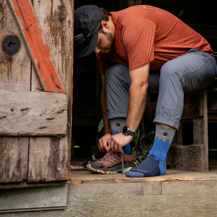 model sitting in doorway putting on his shoes wearing the 1974 number 2 micro crew hiker in twilight