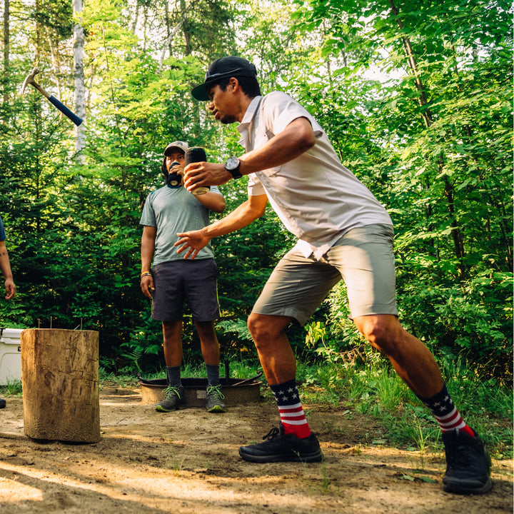 Man having fun at a campsite playing a drinking game wearing Captain Stripe Micro Crew Hiking Socks, Lifestyle Image