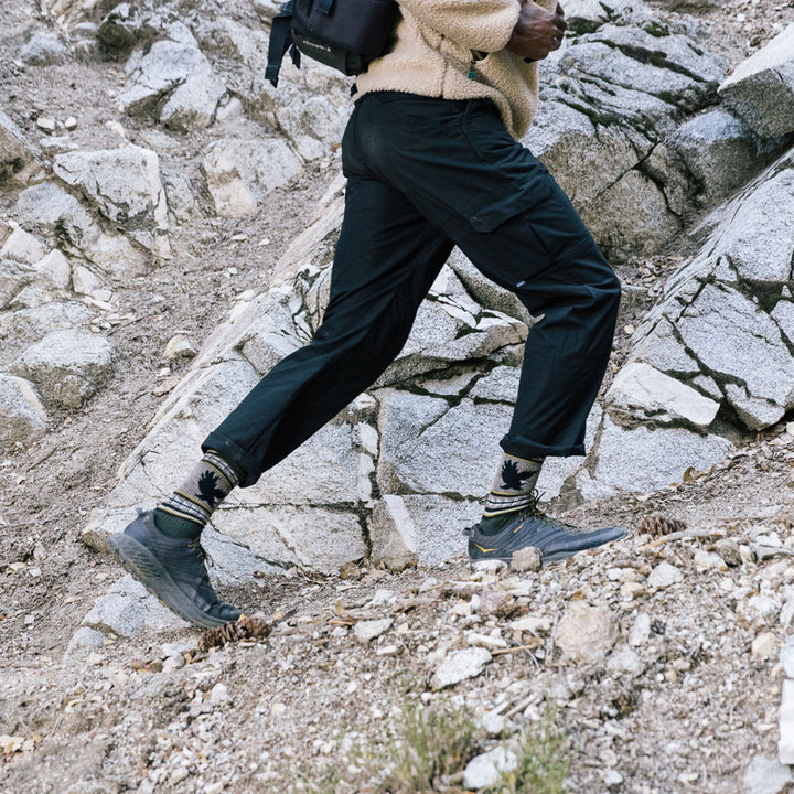 Side shot of model wearing men's vangrizzle boot hiking sock in forest green while hiking on a mountain