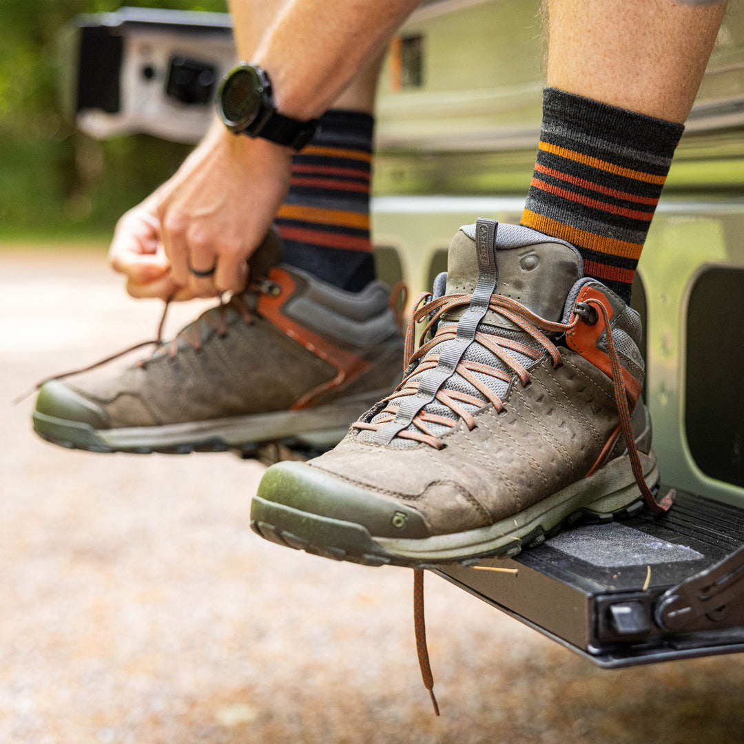 Close up shot of model tying their hiking boots while wearing the men's fastpack micro crew hiking socks in charcoal
