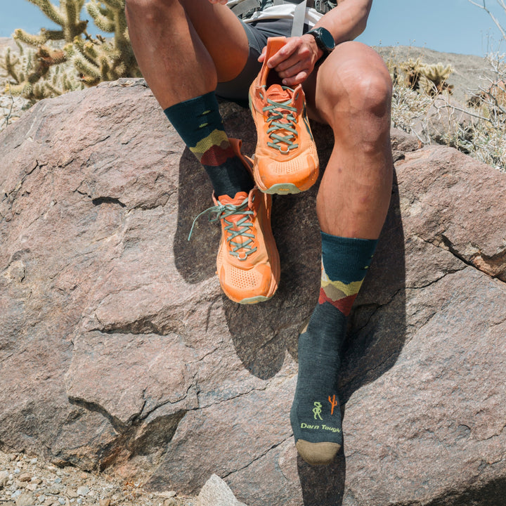 models feet hanging over rock side wearing the 5051 spaced out lightweight micro crew hiking sock in charcoal colorway