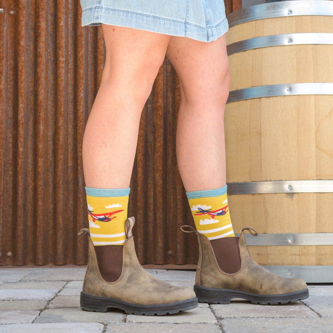 Full body shot of model standing next to barrel wearing the women's animal haus crew lifestyle sock in buttercup