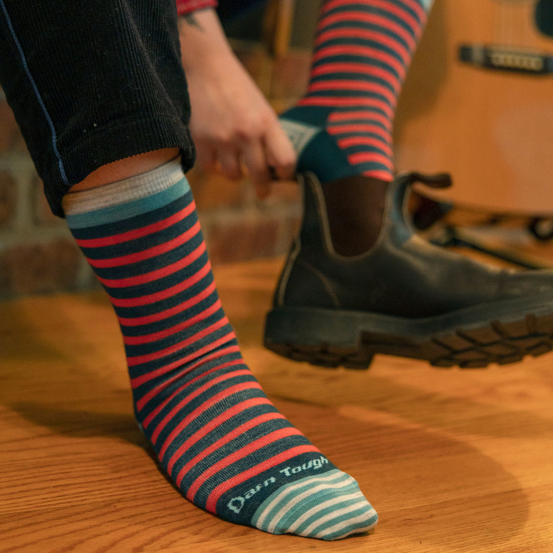 Close up of model wearing women's morgan crew lifestyle sock in dark teal while putting on black short boots