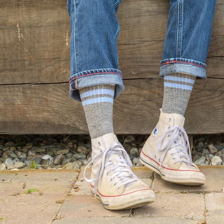 Close up shot of model sitting outside wearing the men's letterman crew lifestyle sock in granite and white sneakers