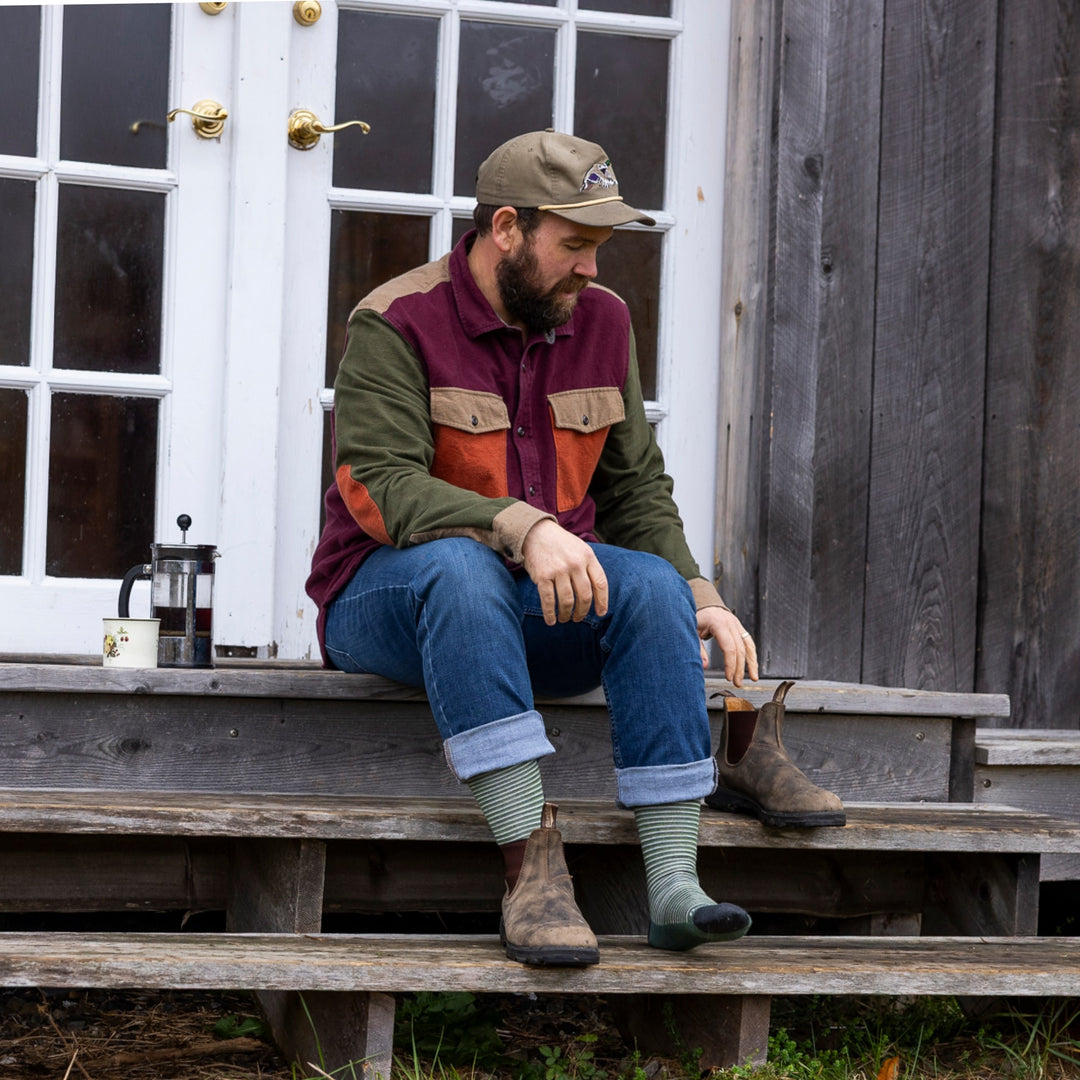 image of man sitting on wood stairs putting on boots wearing 6134 microstripe crew lightweight moss sock