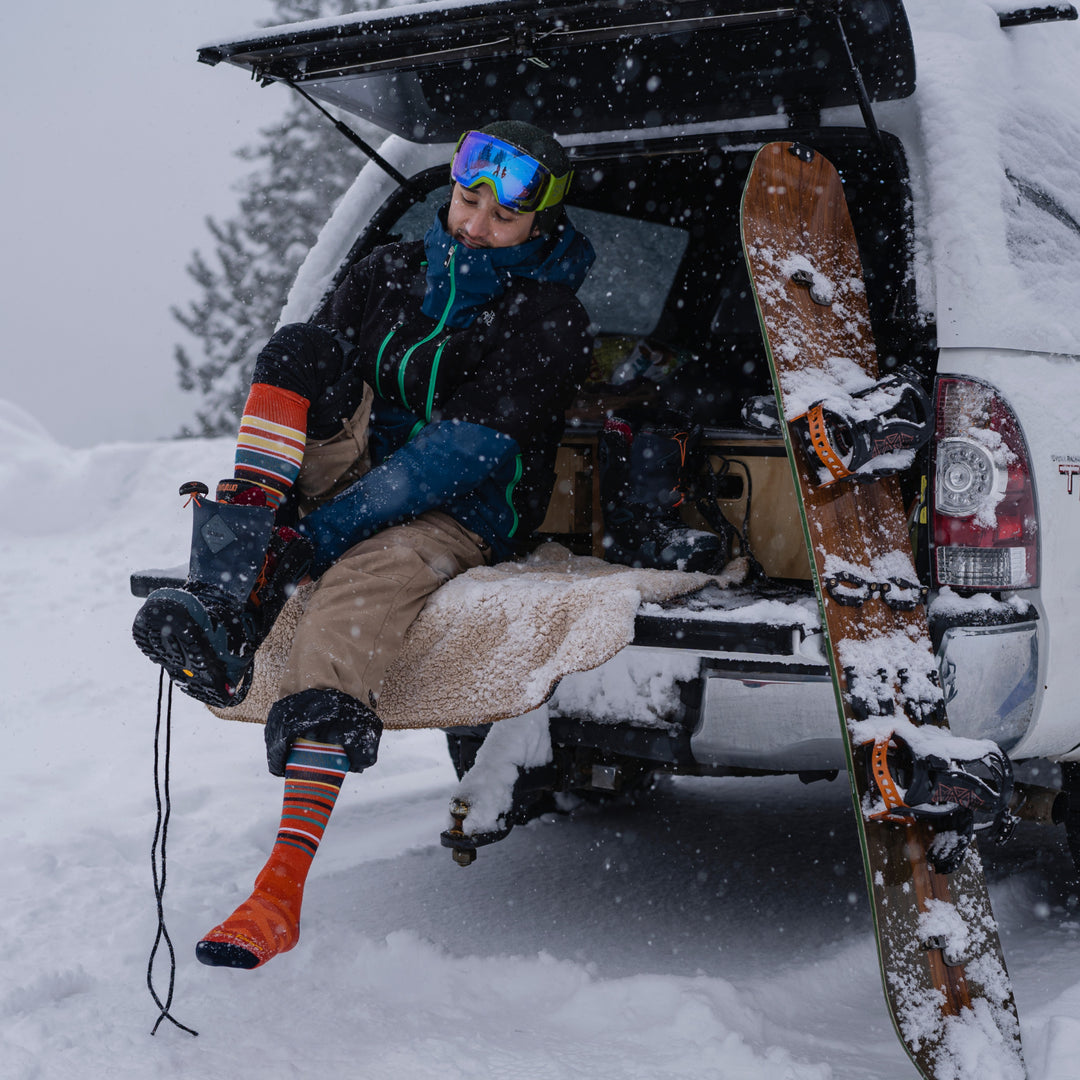 Model sitting on tailgate putting on snowboard boots wearing the 8017 Snowpack in Tiger