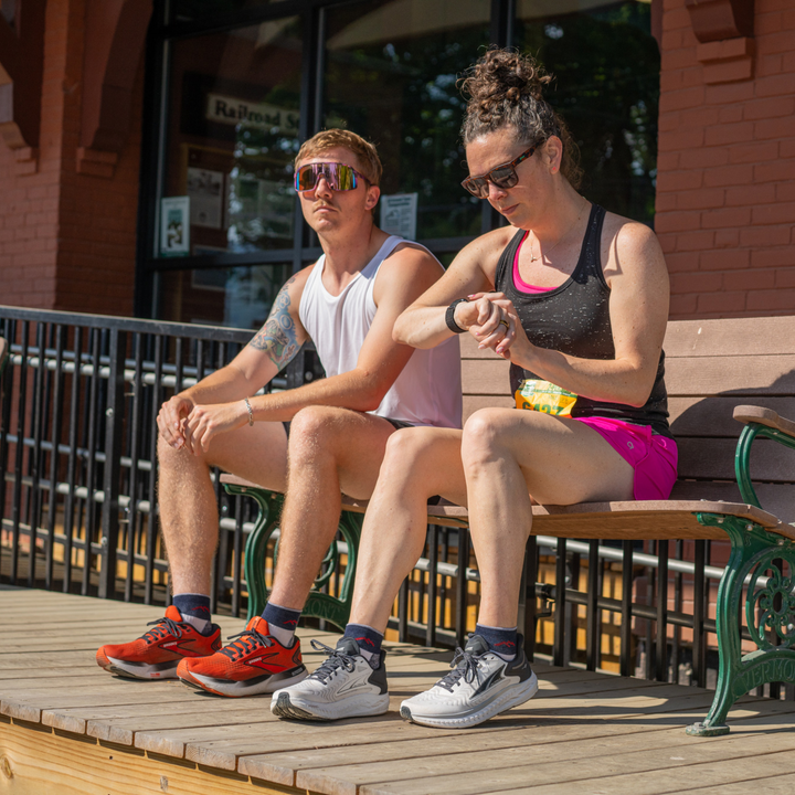 Two models sitting on bench wearing the 1201 natural running sock