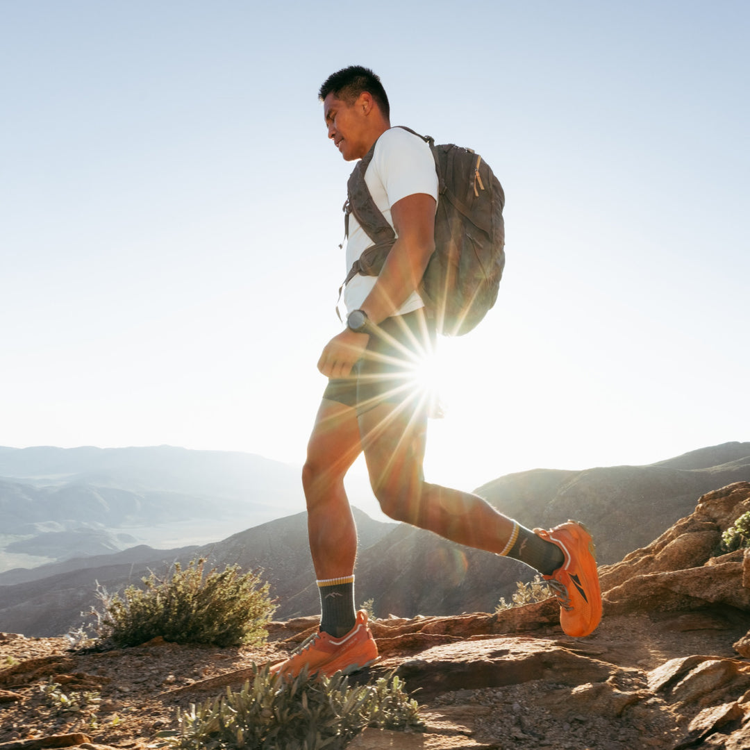 Model walk on the top of the summit wearing the 1466 midweight micro crew hiking sock in spruce colorway