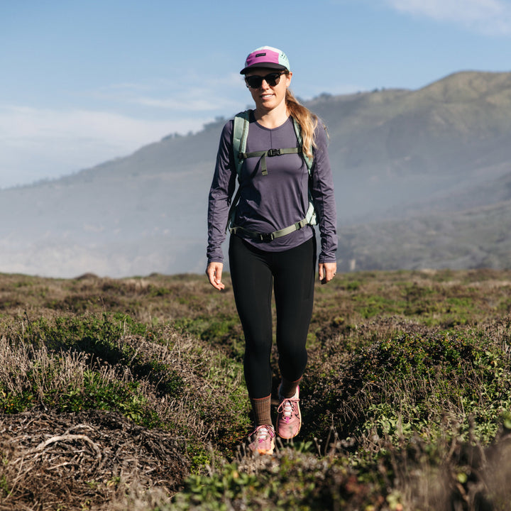 Model hiking across field wearing the 1903 Midweight Micro crew hiking sock in bark