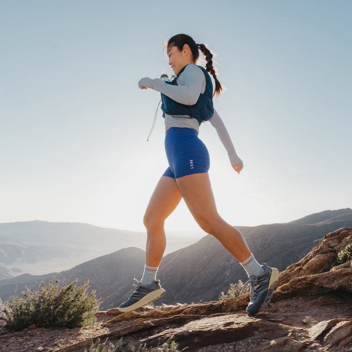 model walking on the top summit wearing the 1903 midweight micro crew hiking sock in glacier colorway