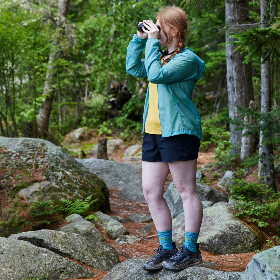 model standing in the woods looking through binoculars wearing the 1943 Aqua