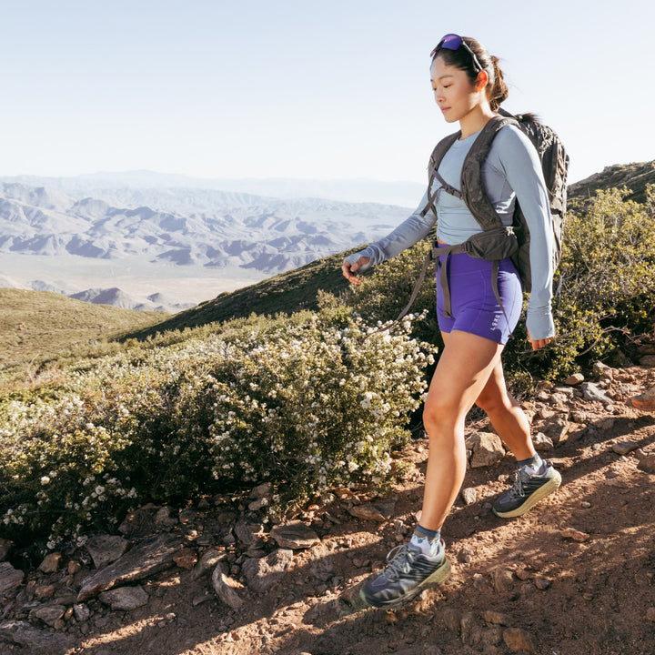 model walking on a hiking trail wearing the 1958 quarter midweight hiking sock in mountain white colorway